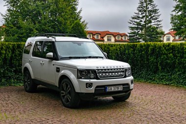Gdansk, Polonya - 30 Ağustos 2025: Avrupa 'nın varlıklı banliyösü. Konut kulübesi ve park etmiş bir Land Rover arabası yeşil lanet parkın arasında.