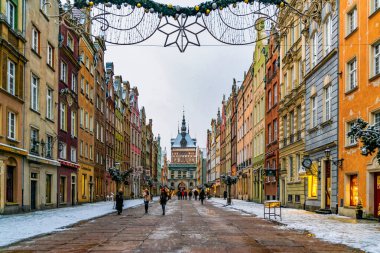 Gdansk, Polonya - 20 Ocak 2022: Gdansk 'taki Dluga caddesindeki güzel renkli antik evler ve tarihi binalar. Noel süslenmiş sokakta yürüyen turistler