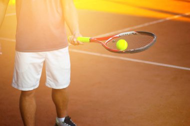 Arka planda güneş ışığı ile tenis top yakın çekim tutan adam