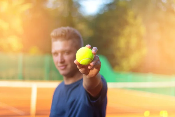 Uomo spettacolo tennis close-up palla con la luce del sole in background — Foto Stock