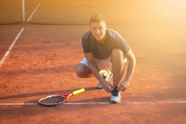 Giocatore professionista di tennis che lega le scarpe da ginnastica sul campo per la partita con la luce solare in background — Foto Stock