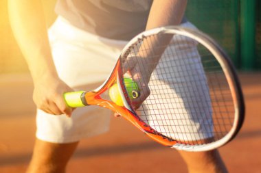 Bir tenis topu bir maç sırasında arka planda güneş ışığı ile hizmet etmek bir tenis oyuncusu hazırlar