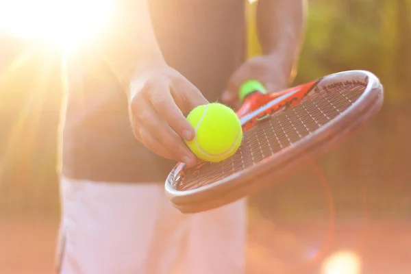 Un tennista si prepara a servire una palla da tennis durante una partita con la luce del sole sullo sfondo — Foto Stock