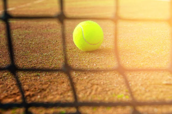 Palla da tennis close-up e rete sul campo con luce solare sullo sfondo — Foto Stock