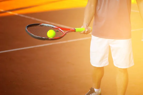 Uomo che tiene la palla da tennis gialla da vicino con la luce del sole sullo sfondo — Foto Stock