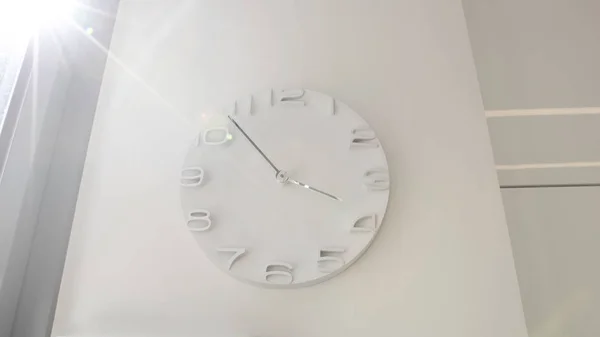 Reloj de madera blanco en la pared blanca con luz cálida en la mañana —  Fotos de Stock