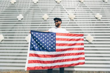 Mutlu hipster adam Amerikan veya ABD bayrağı tutarak. O rahat kıyafetler giyiyor.