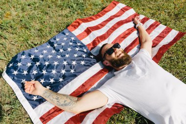Mutlu hipster adam Amerikan veya ABD bayrağı tutarak. O rahat kıyafetler giyiyor.