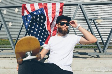 Mutlu hipster adam Amerikan veya ABD bayrağı tutarak. O rahat kıyafetler giyiyor.