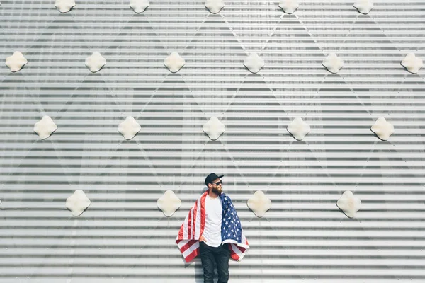 Happy hipster man holding American or USA flag. He is wearing casual clothes.