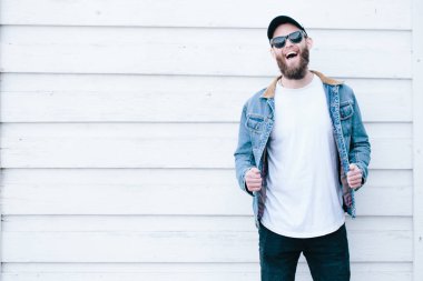 Siyah kot pantolon, tişört ve bir beyzbol şapkası giyen yürüyen hipster adam