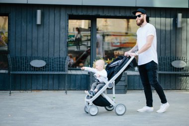 Babası bir bebek arabası ve bir bebek şehir sokaklarında yürüyüş