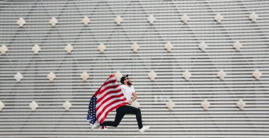 Mutlu hipster adam Amerikan veya ABD bayrağı tutarak. O rahat kıyafetler giyiyor.