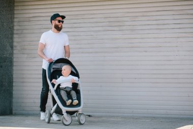 Babası bir bebek arabası ve bir bebek şehir sokaklarında yürüyüş