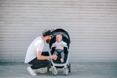 Babası bir bebek arabası ve bir bebek şehir sokaklarında yürüyüş