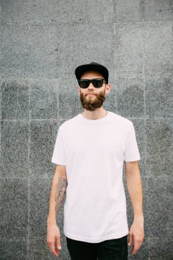 Hipster yakışıklı erkek model beyaz boş t-shirt ve logonuzu yeri olan bir beyzbol şapkası giyen sakallı