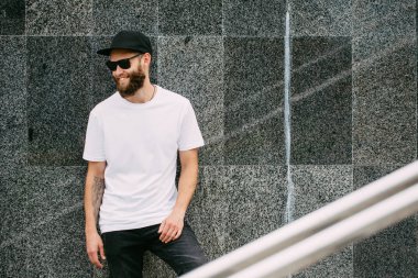 Hipster yakışıklı erkek model beyaz boş t-shirt ve logonuzu yeri olan bir beyzbol şapkası giyen sakallı