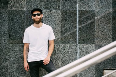 Hipster yakışıklı erkek model beyaz boş t-shirt ve logonuzu yeri olan bir beyzbol şapkası giyen sakallı