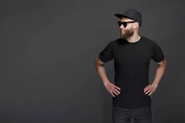 Hipster handsome male model with beard wearing black blank baseball cap with space for your logo — Stock Photo, Image