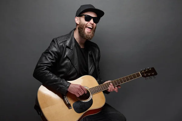 Gitarrist singt im Musikstudio. Hipster-Gitarrist mit Bart und schwarzer Kleidung spielt Akustikgitarre — Stockfoto