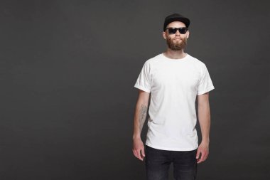 Sakallı, beyaz, boş tişörtlü, beysbol şapkalı, logonuz için yeri olan yakışıklı bir hippi mankeni.