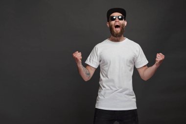 Sakallı, beyaz, boş tişörtlü, beysbol şapkalı, logonuz için yeri olan yakışıklı bir hippi mankeni.