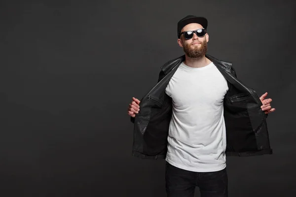 Hipster pohledný mužský model s vousy v bílém prázdném tričku a baseballovou čepicí s prostorem pro vaše logo nebo design v neformálním městském stylu — Stock fotografie