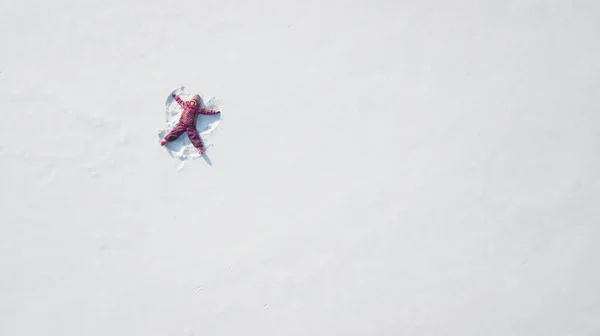 Un ragazzino che fa un angelo della neve. Punto di vista alto. Vista aerea — Foto Stock