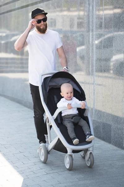 Отец гулял с коляской и ребенком по улицам города — стоковое фото