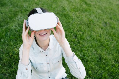 Yeşil çim üzerinde sanal gerçeklik gözlük kullanan kadın