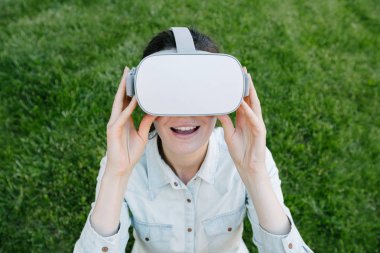 Yeşil çim üzerinde sanal gerçeklik gözlük kullanan kadın