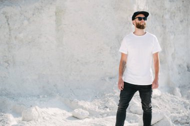 Sakallı, beyaz, boş tişörtlü, beysbol şapkalı, logonuz için yeri olan yakışıklı bir hippi mankeni.