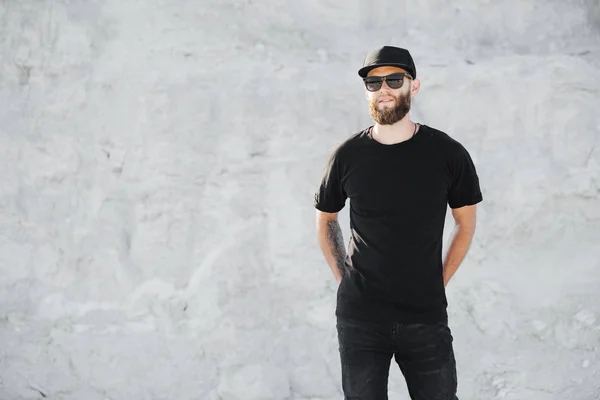 Hipster knappe mannelijke model met baard dragen zwarte witte t-shirt met ruimte voor uw logo of ontwerp in casual stedelijke stijl — Stockfoto