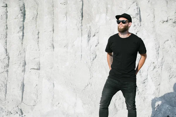 Hipster knappe mannelijke model met baard dragen zwarte witte t-shirt met ruimte voor uw logo of ontwerp in casual stedelijke stijl — Stockfoto