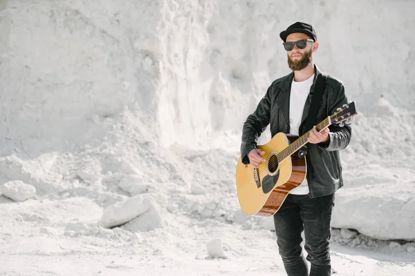 Guitarrista a cantar lá fora. Hipster guitarrista com barba e roupas pretas — Fotografia de Stock