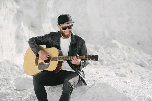 Guitarrista a cantar lá fora. Hipster guitarrista com barba e roupas pretas — Fotografia de Stock