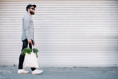 Elinde bakkalla dolu bir eko çanta tutan adam. Sebze ve meyveler. Ekoloji kavramı çevre koruma.