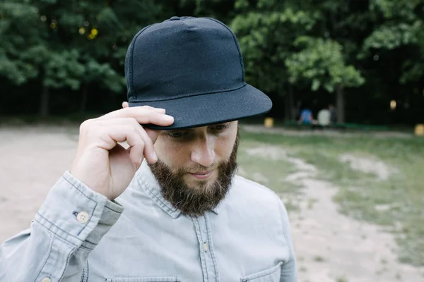 Hipster handsome male model with beard wearing black blank baseball cap with space for your logo — Stock Photo, Image
