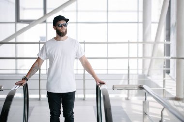 Sakallı, beyaz, boş tişörtlü, beysbol şapkalı, logonuz için yeri olan yakışıklı bir hippi mankeni.