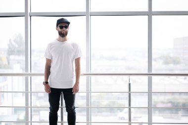 Sakallı, beyaz, boş tişörtlü, beysbol şapkalı, logonuz için yeri olan yakışıklı bir hippi mankeni.