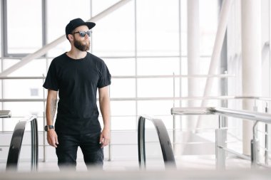 Hippi, sakallı, siyah, boş tişörtlü, logonuz için yeri olan yakışıklı bir erkek model.