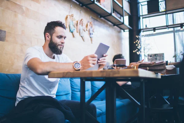 Mann mit Tablet-PC im Restaurant oder Café. er trägt ein weißes T-Shirt und sitzt an einem Tisch — Stockfoto