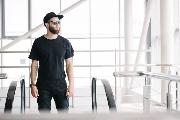 Hipster όμορφο ανδρικό μοντέλο με γενειάδα φορώντας μαύρο λευκό t-shirt με χώρο για το λογότυπο ή το σχέδιό σας σε casual αστικό στυλ — Φωτογραφία Αρχείου