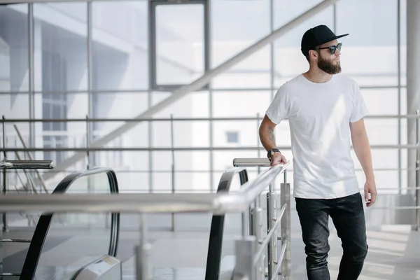 Hipster gutaussehendes männliches Model mit Bart trägt weißes Blank-T-Shirt und Baseballmütze mit Platz für Ihr Logo oder Design im lässigen urbanen Stil — Stockfoto