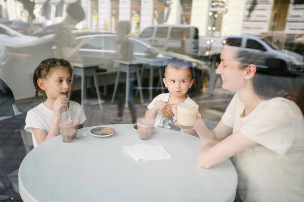 Anya gyermekek forró csokoládét és latte a helyi kávézóban. Mosolyognak, és a szórakozás. — Stock Fotó