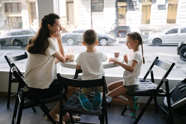 Anya gyermekek forró csokoládét és latte a helyi kávézóban. Mosolyognak, és a szórakozás. — Stock Fotó