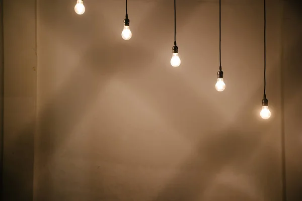 Glühbirnen über weißem Wandhintergrund — Stockfoto
