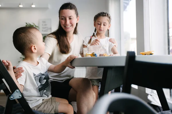 Moeder met kinderen die warme chocolademelk en Latte drinken in een lokale koffieshop. Ze glimlachen en hebben plezier. — Stockfoto