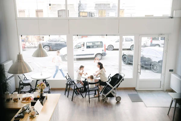 Mother with children drinking hot chocolate and latte at a local coffee shop. They are smiling and having fun. — Stock Photo, Image