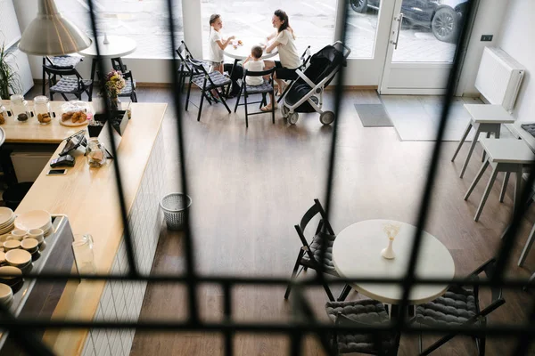 Mutter mit Kindern trinkt heiße Schokolade und Latte in einem örtlichen Café. Sie lächeln und haben Spaß. — Stockfoto